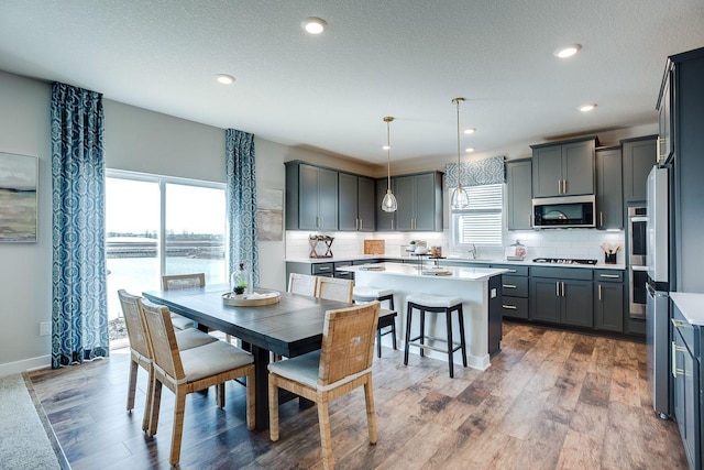 dining room featuring a textured ceiling, dark hardwood / wood-style flooring, sink, and a water view