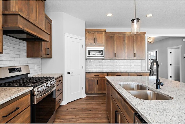 kitchen featuring stainless steel appliances, custom exhaust hood, backsplash, hanging light fixtures, and dark hardwood / wood-style flooring