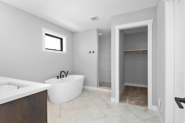 bathroom with tile flooring, plus walk in shower, a textured ceiling, and vanity