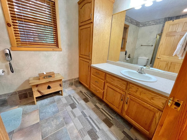 29724 387th St, Waubun, MN 56589 - bathroom featuring vanity, toilet, stone finish floors, and a shower with door