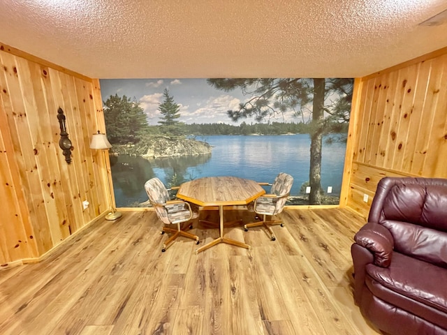 29724 387th St, Waubun, MN 56589 - dining space featuring a textured ceiling, wooden walls, wood finished floors, and a water view