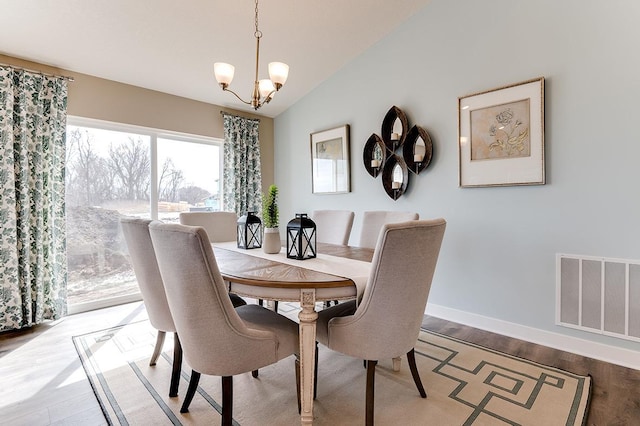 dining room with a notable chandelier, light wood-type flooring, and lofted ceiling