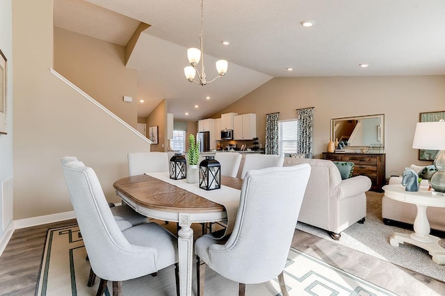 dining area with a notable chandelier, wood-type flooring, and vaulted ceiling