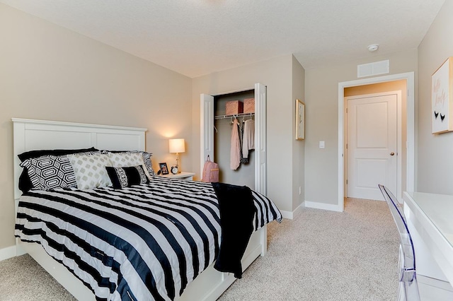 bedroom featuring light carpet, a textured ceiling, and a closet