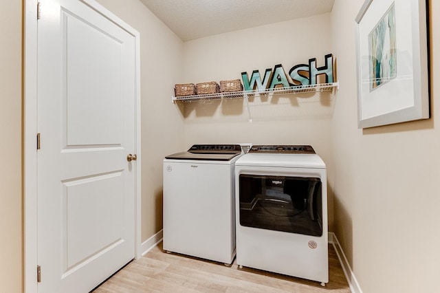 laundry area featuring a textured ceiling, light hardwood / wood-style floors, and washer and dryer