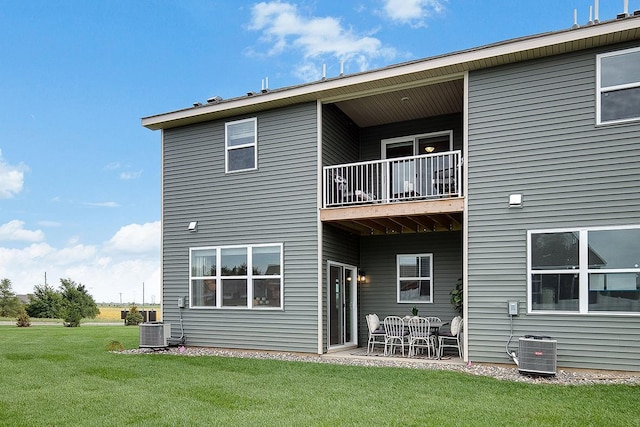 back of property with a yard, central air condition unit, a balcony, and a patio area