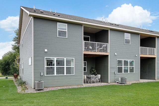 back of property with central air condition unit, a patio, a yard, and a balcony