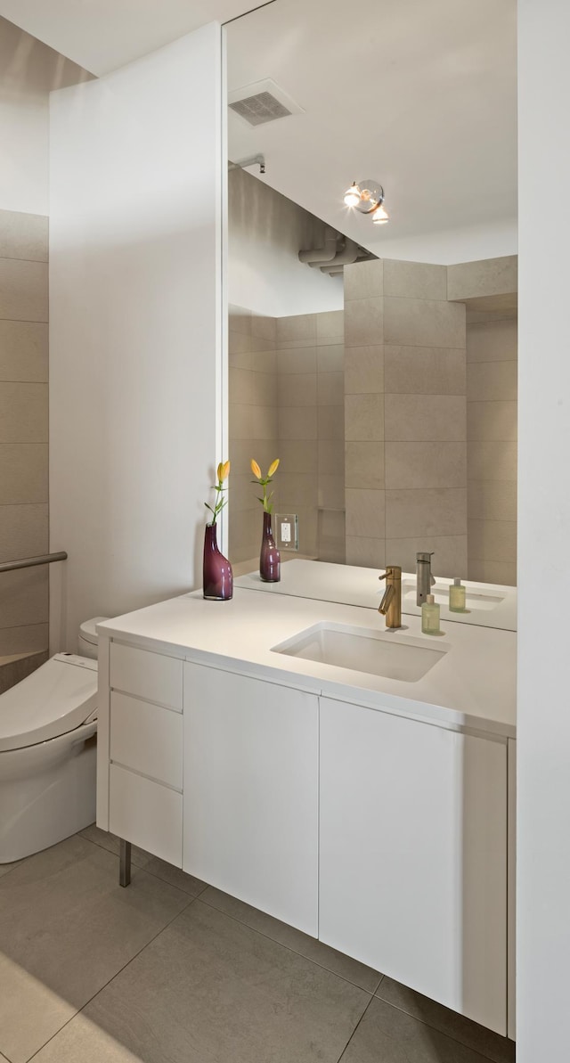 bathroom featuring vanity, toilet, tile patterned flooring, and tile walls