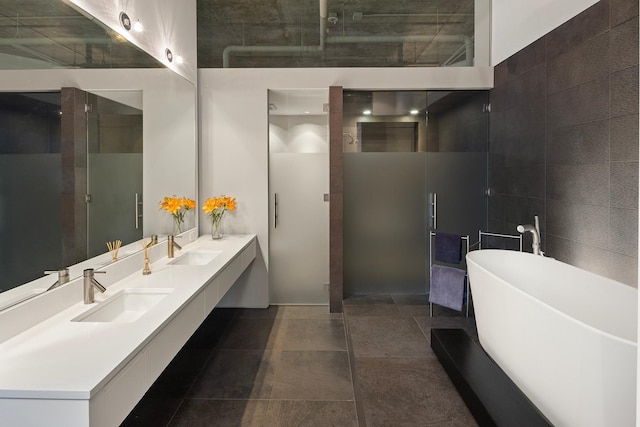 bathroom with a bathing tub, tile walls, vanity, and tile patterned floors