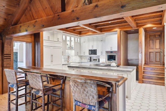 17950 Breezy Point Rd, Woodland, MN 55391 - kitchen with built in appliances, wood ceiling with exposed beams, a kitchen island, white cabinetry, and decorative backsplash