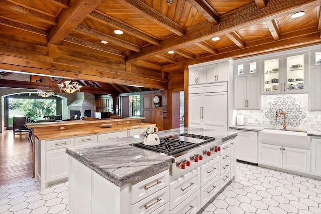 17950 Breezy Point Rd, Woodland, MN 55391 - kitchen featuring wood ceiling with exposed beams, a kitchen island, stainless steel gas stovetop, a sink, and a chandelier