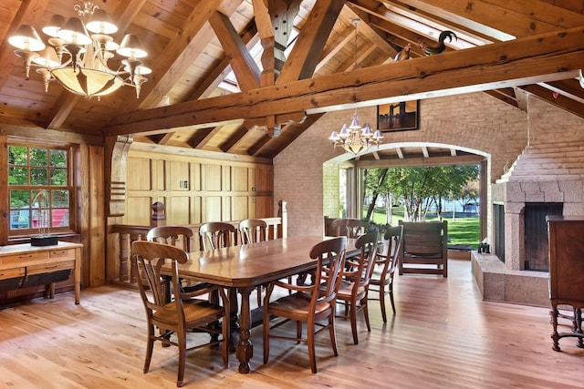 17950 Breezy Point Rd, Woodland, MN 55391 - dining area with a chandelier, wood-type flooring, wooden ceiling with exposed beams, high vaulted ceiling, and a fireplace with raised hearth