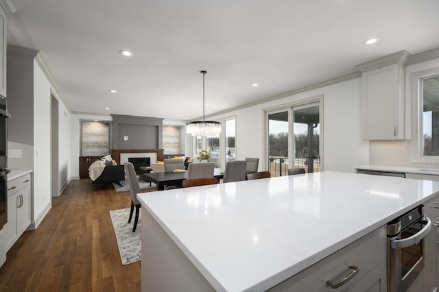 kitchen with crown molding, a center island, dark hardwood / wood-style floors, and decorative light fixtures