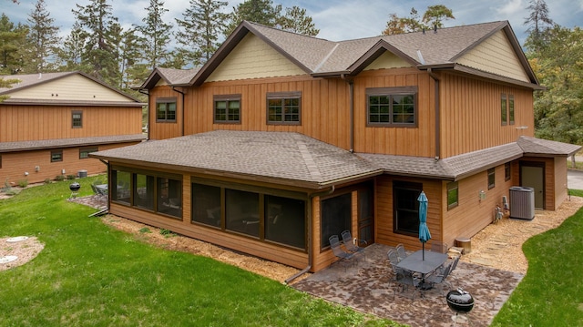 rear view of property with a lawn, a sunroom, and central AC unit