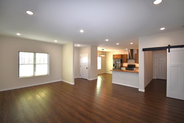 unfurnished living room with dark wood-type flooring and a barn door