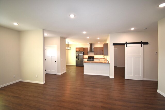 unfurnished living room with dark hardwood / wood-style floors and a barn door