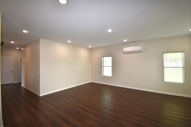 empty room with a wall mounted AC and dark hardwood / wood-style floors