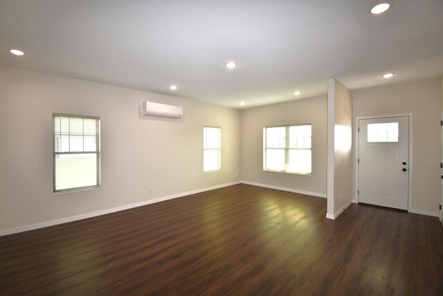 interior space featuring a wall mounted air conditioner, plenty of natural light, and dark hardwood / wood-style floors