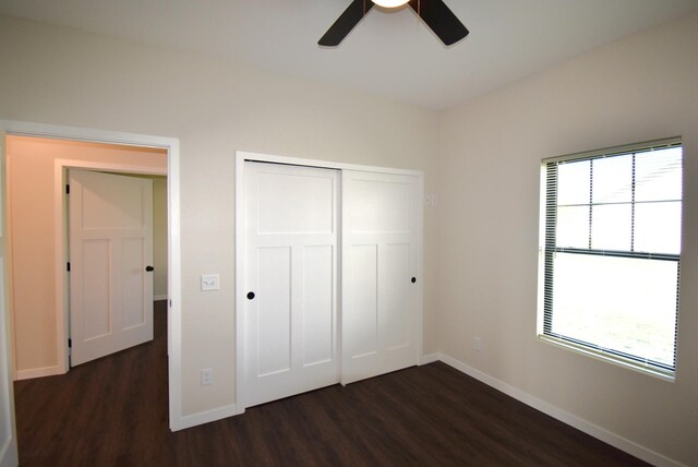 unfurnished bedroom featuring a closet, dark hardwood / wood-style flooring, multiple windows, and ceiling fan