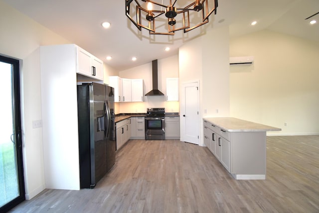 kitchen with white cabinets, kitchen peninsula, wall chimney exhaust hood, light hardwood / wood-style flooring, and appliances with stainless steel finishes