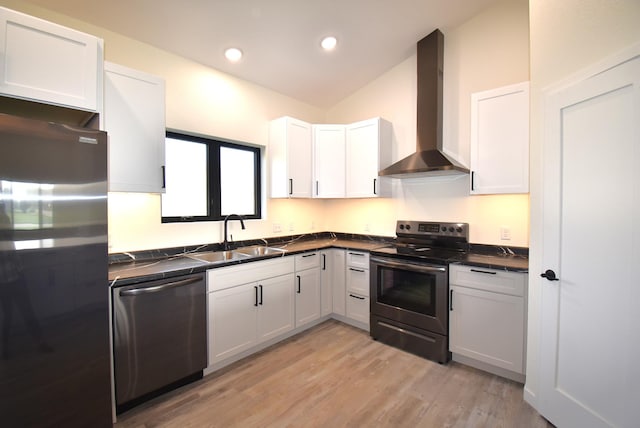 kitchen featuring wall chimney exhaust hood, stainless steel appliances, and white cabinetry