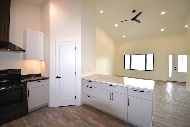 kitchen featuring white cabinetry, electric stove, high vaulted ceiling, hardwood / wood-style floors, and wall chimney range hood