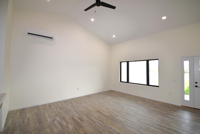 empty room with hardwood / wood-style flooring, plenty of natural light, ceiling fan, and a wall mounted AC