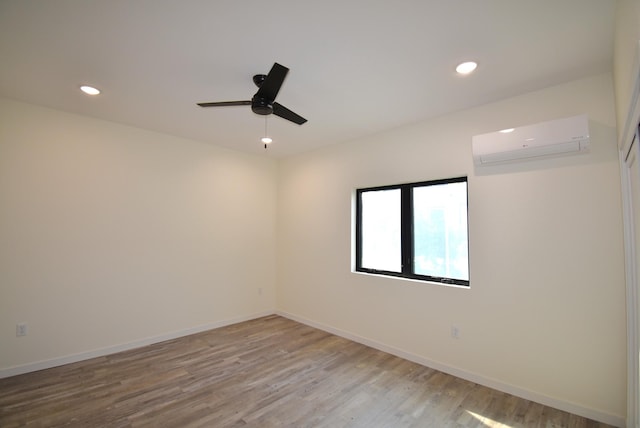 spare room with light hardwood / wood-style floors, a wall unit AC, and ceiling fan