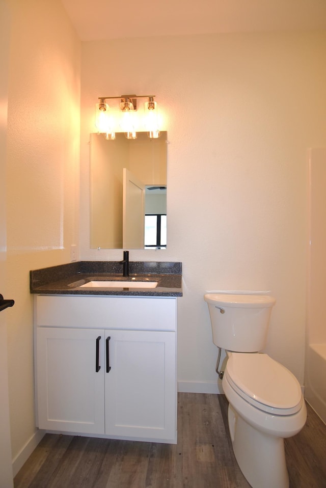 bathroom with wood-type flooring, vanity, a bathing tub, and toilet