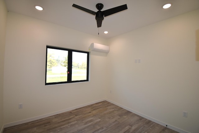 spare room featuring ceiling fan, hardwood / wood-style flooring, and a wall mounted AC