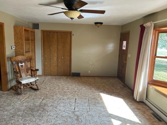 306 9th St, Westbrook, MN 56183 - spare room featuring baseboard heating, a ceiling fan, and light colored carpet