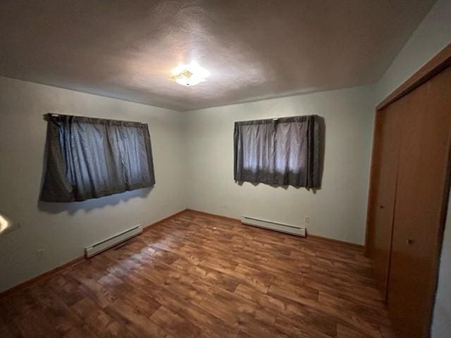 unfurnished bedroom featuring a closet, hardwood / wood-style flooring, and a baseboard radiator