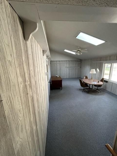 306 9th St, Westbrook, MN 56183 - living area with a skylight, carpet flooring, lofted ceiling, wood walls, and a ceiling fan