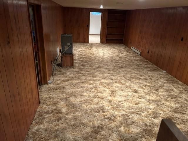 interior space featuring a baseboard radiator, wooden walls, and carpet