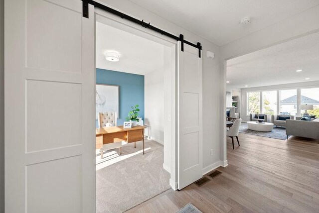 hallway featuring a barn door and light colored carpet