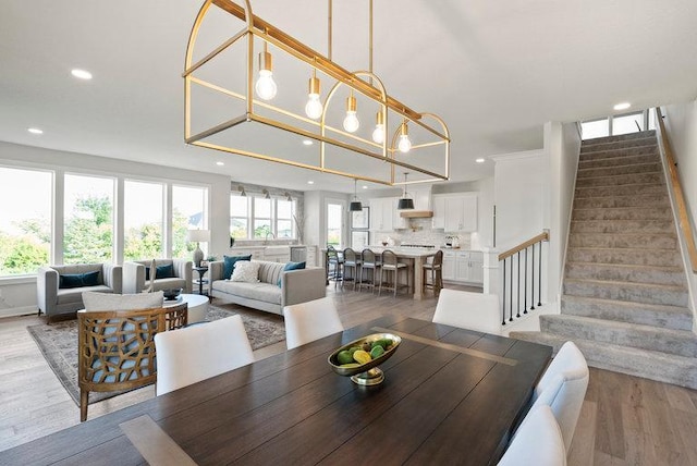 dining room with recessed lighting, light wood finished floors, and stairs