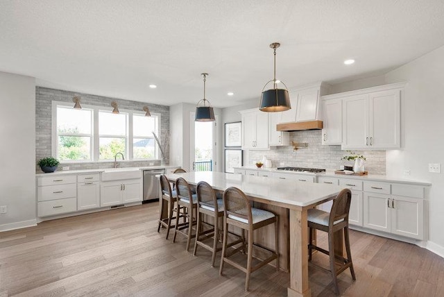 kitchen with tasteful backsplash, light countertops, dishwasher, and light wood-style flooring