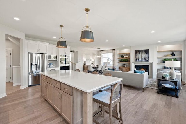 kitchen with light wood finished floors, a breakfast bar area, light countertops, appliances with stainless steel finishes, and a kitchen island