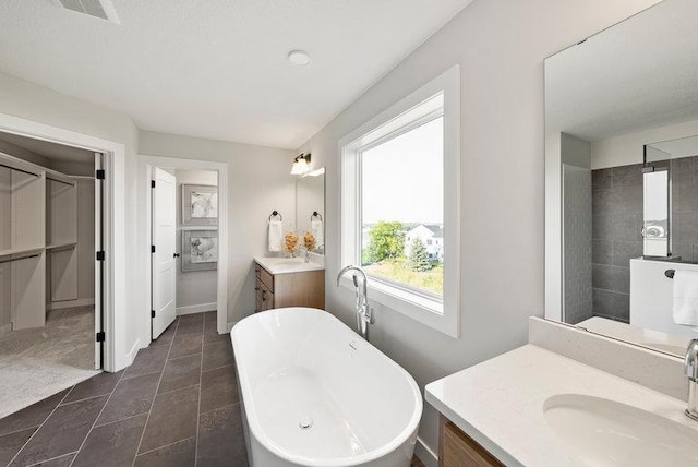 bathroom featuring a soaking tub, two vanities, visible vents, a sink, and baseboards