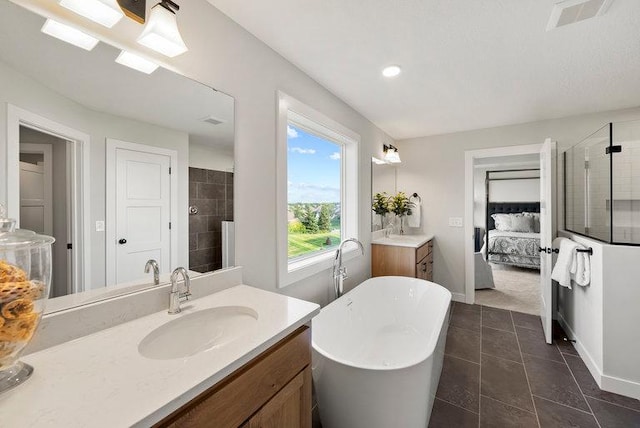 ensuite bathroom with a freestanding tub, connected bathroom, a sink, visible vents, and tiled shower