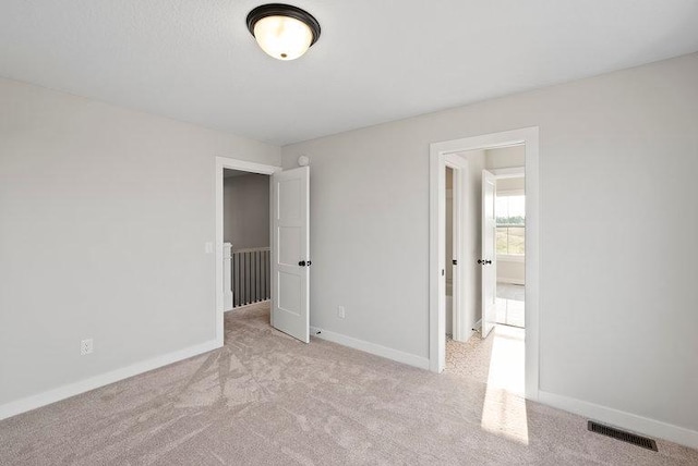 unfurnished bedroom with carpet, visible vents, and baseboards