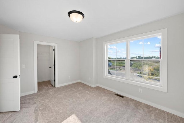 empty room featuring baseboards, visible vents, and light colored carpet