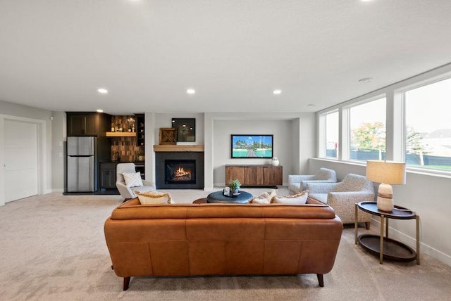 living room with recessed lighting, a lit fireplace, baseboards, and light colored carpet