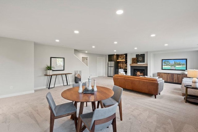 dining space featuring recessed lighting, stairway, light carpet, a warm lit fireplace, and baseboards