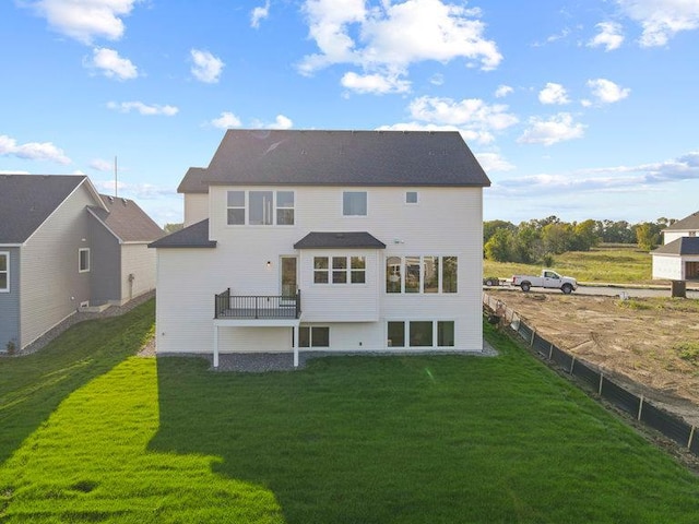 rear view of house with fence and a lawn