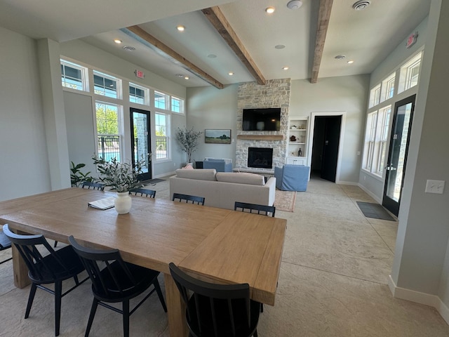 dining area featuring a stone fireplace, beamed ceiling, recessed lighting, and baseboards