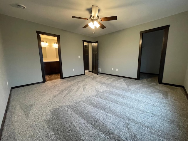 unfurnished bedroom with light carpet, a spacious closet, ensuite bath, and ceiling fan