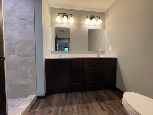 bathroom with wood-type flooring, walk in shower, vanity, and toilet