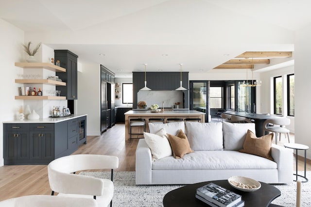 living room featuring vaulted ceiling with beams, wine cooler, and light hardwood / wood-style floors