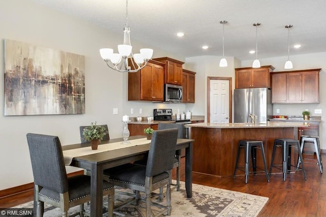 kitchen featuring dark hardwood / wood-style floors, a chandelier, stainless steel appliances, and pendant lighting